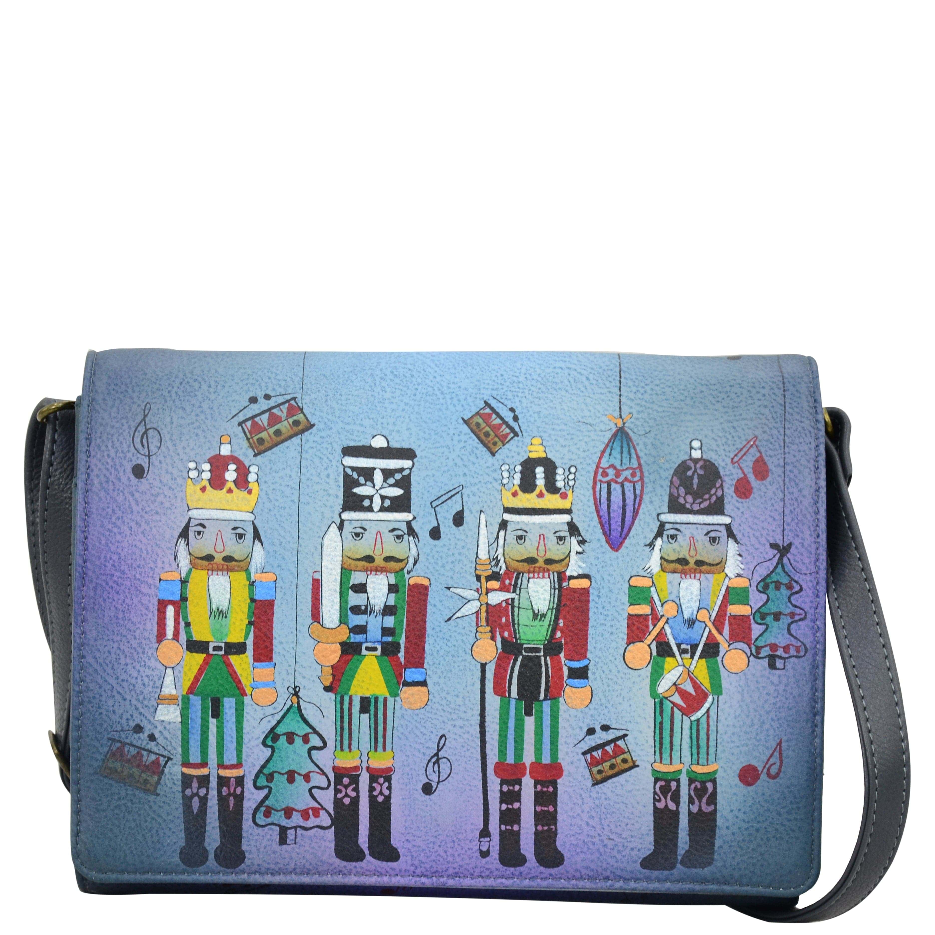 Anna by Anuschka style 8292, handpainted Multi Compartment Flap Crossbody. Nutcracker Party painting in blue color. Featuring flap with snap button entry to three open and one zippered compartment, Fits E-Reader, Hands-free.